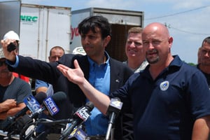 Louisiana Gov. Bobby Jindal, front left, holds up a tar ball while Bernard Parish President Craig Taffaro, front right, begs BP and the U.S. Coast Guard to deploy more booms to protect fragile wetlands at a press conference in Hopedale, La., on May 7, 2010. (Mira Oberman/AFP/Getty Images)