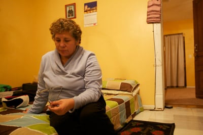 Rosa sits on the mattress in the room she rents with her boyfriend. The trap she sets for rats is visible on the floor near the door frame. (Sally Ryan for ProPublica)