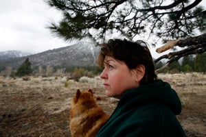 Rita Richardson of Gardnerville, Nev., rests beneath a tree as it begins to snow. She walks to a spot in the mountains near her home where she has shaped a heart in small stones. She feels connected to her late husband Rod Richardson, who was killed in Iraq when his convoy was struck by an IED on Oct. 6, 2006. (Francine Orr/ Los Angeles Times)