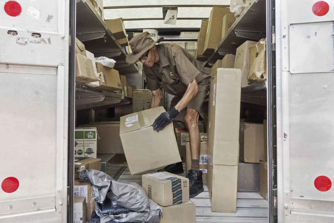 A UPS worker sorts packages in the back of his truck. UPS, DHL and FedEx lobbied Congress to raise the “de minimis threshold” –– the dollar value below which imports wouldn’t be subject to duties or the paperwork required of larger shipments.