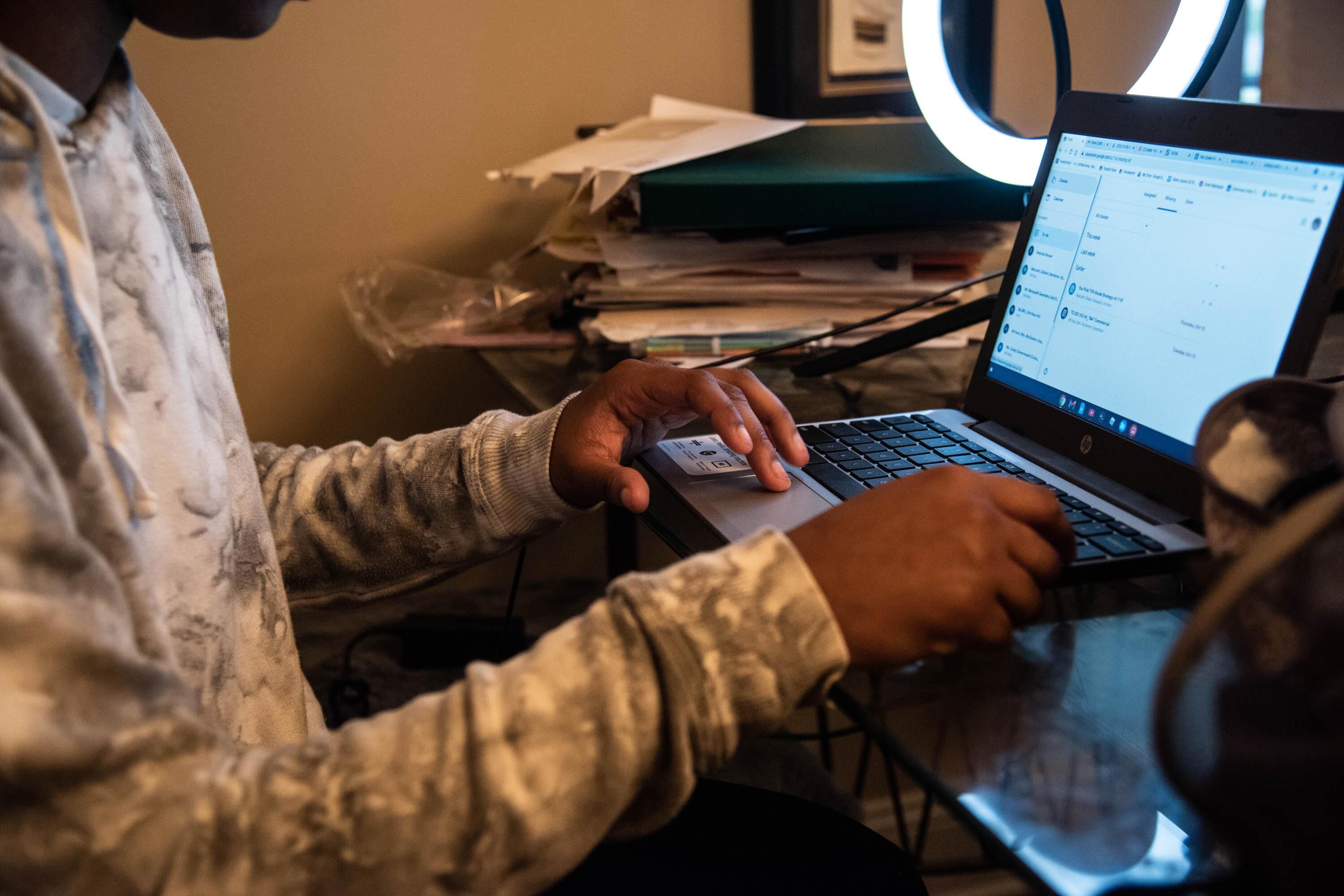 A girl sitting at a desk in front of a laptop.