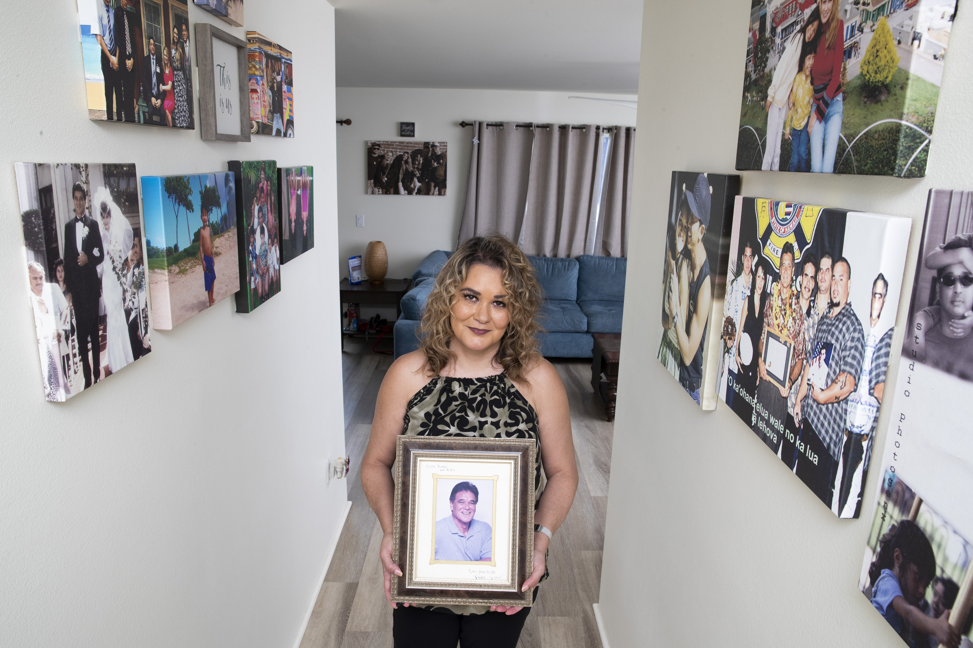 A woman stands in a hallway hung with family photos.