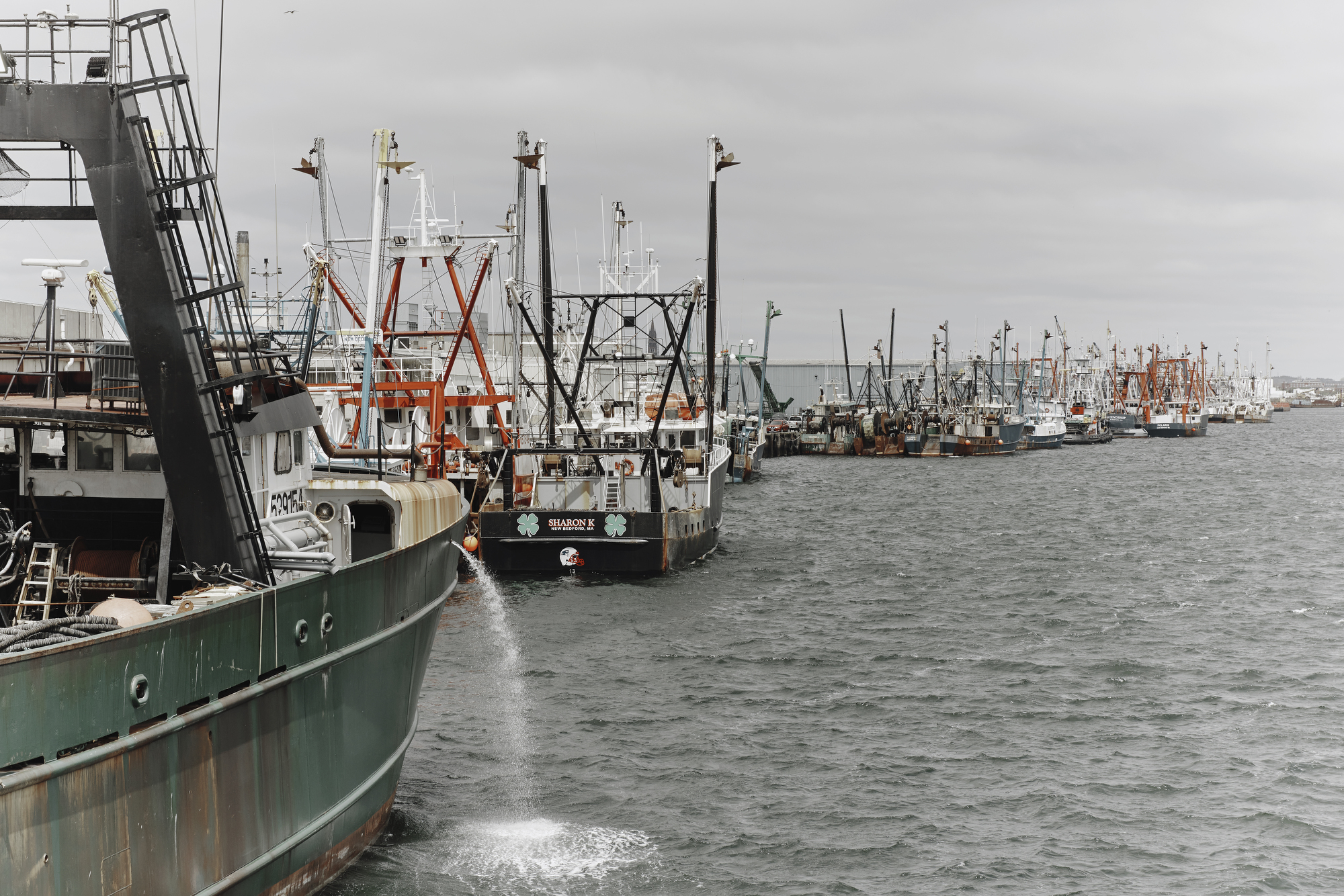 A long line of fishing boats stopped side-by-side stretches into the distance.