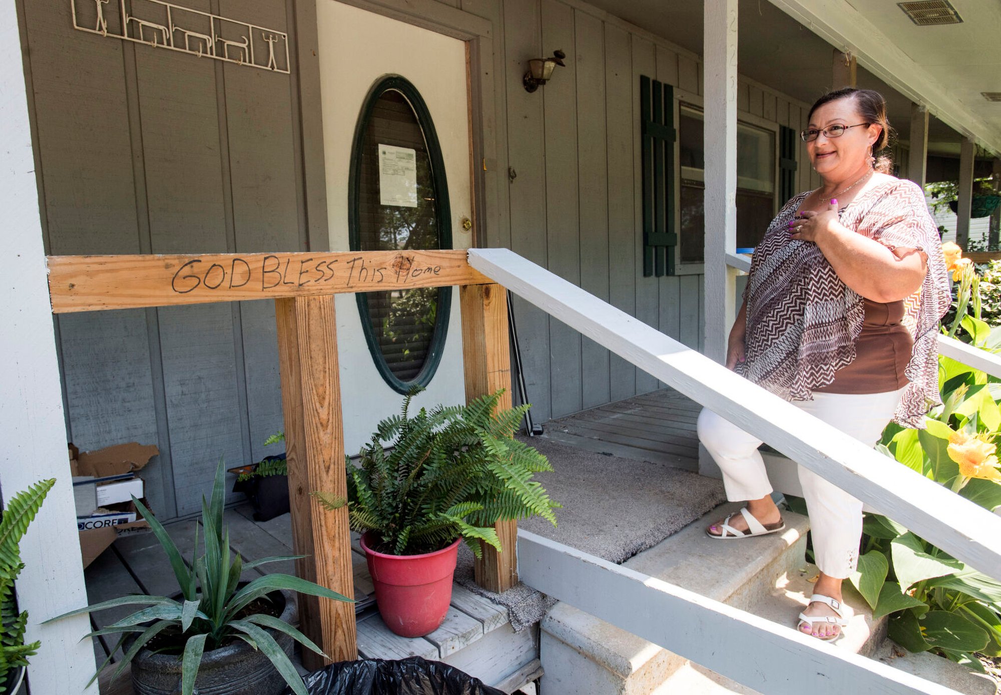 Ned is on the steps of a gray house with vertical siding. On the raw wood of a temporary railing, someone has written 