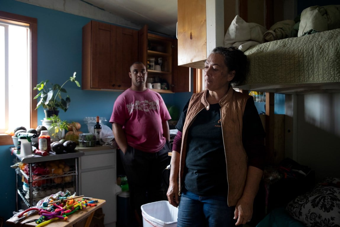 A woman and man stand near a loft bed in a house.