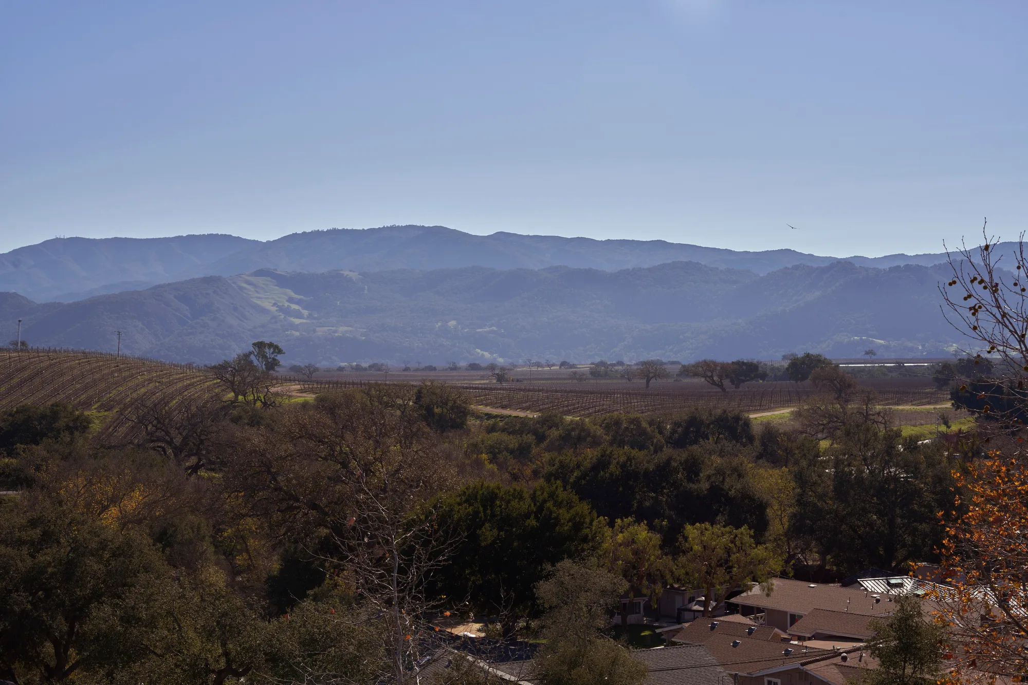 Houses and farms sit in a valley below low mountains.