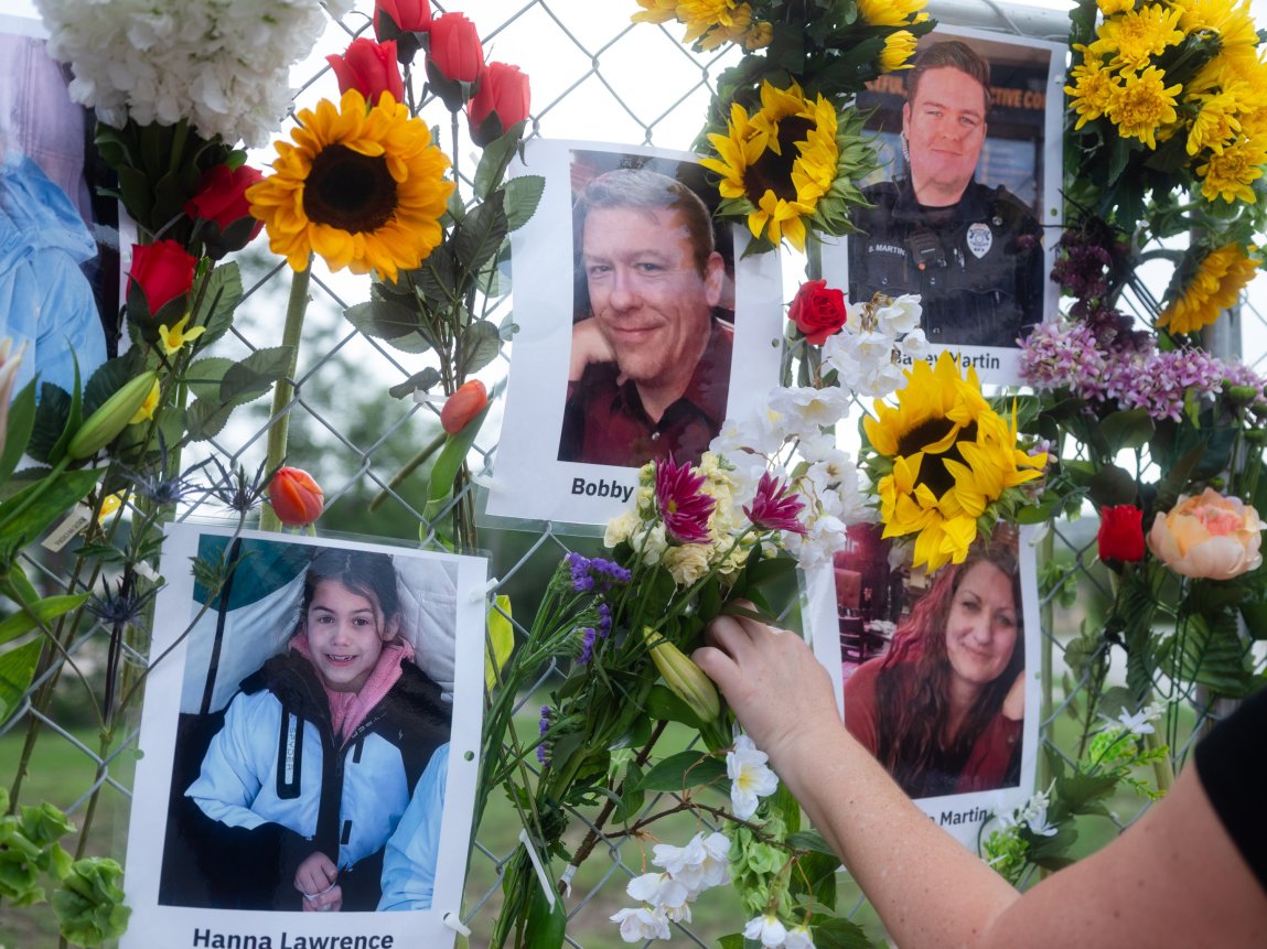 Photos and flowers hang on a fence as a memorial to flood victims.