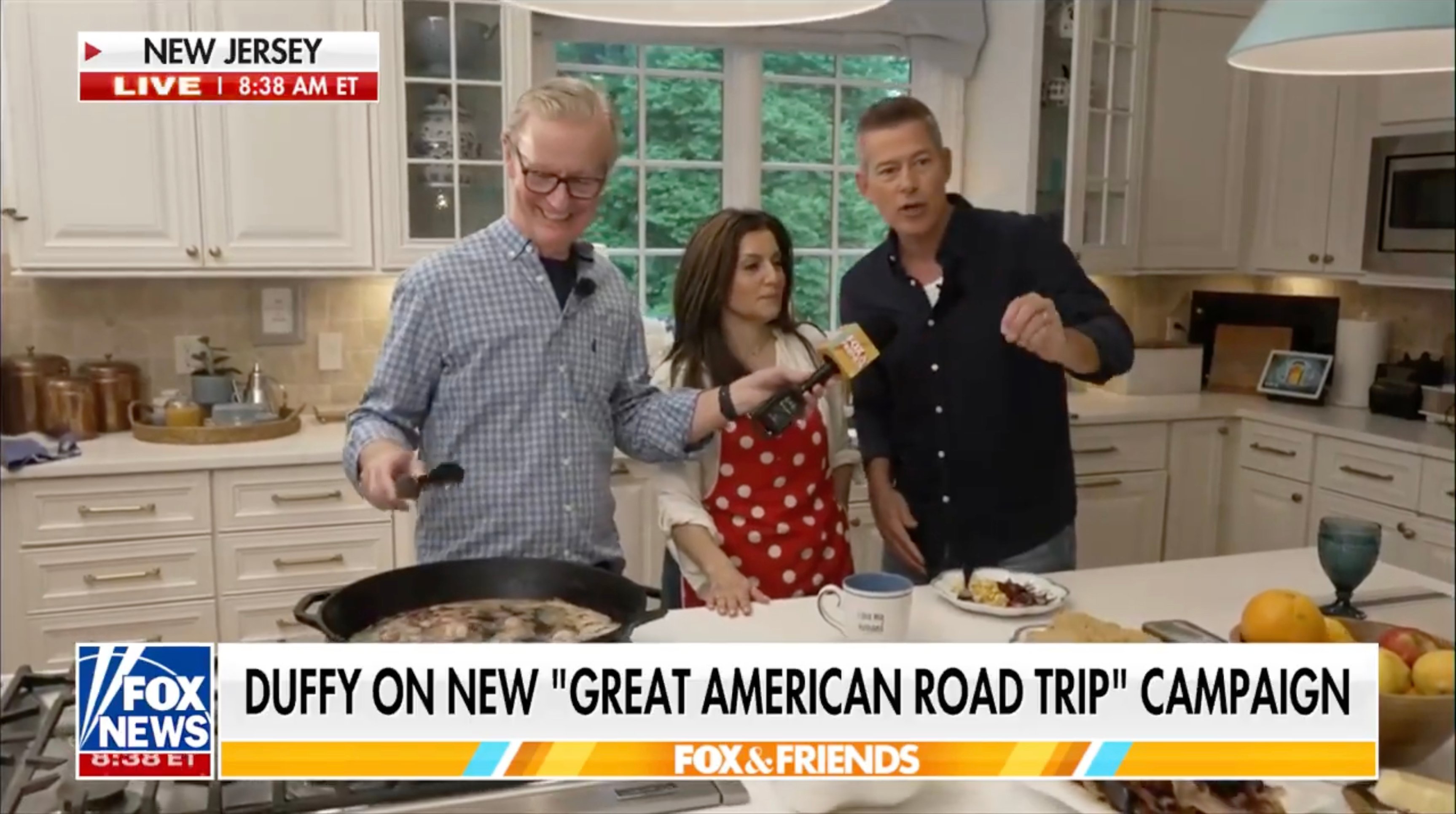 A screenshot from “A Fox & Friends” segment where the host, Rachel Campos-Duffy and Sean Duffy are in a kitchen cooking breakfast.