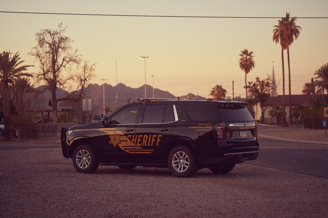 Un SUV de la Oficina del Alguacil del Condado de Maricopa está estacionado en un barrio con palmeras.