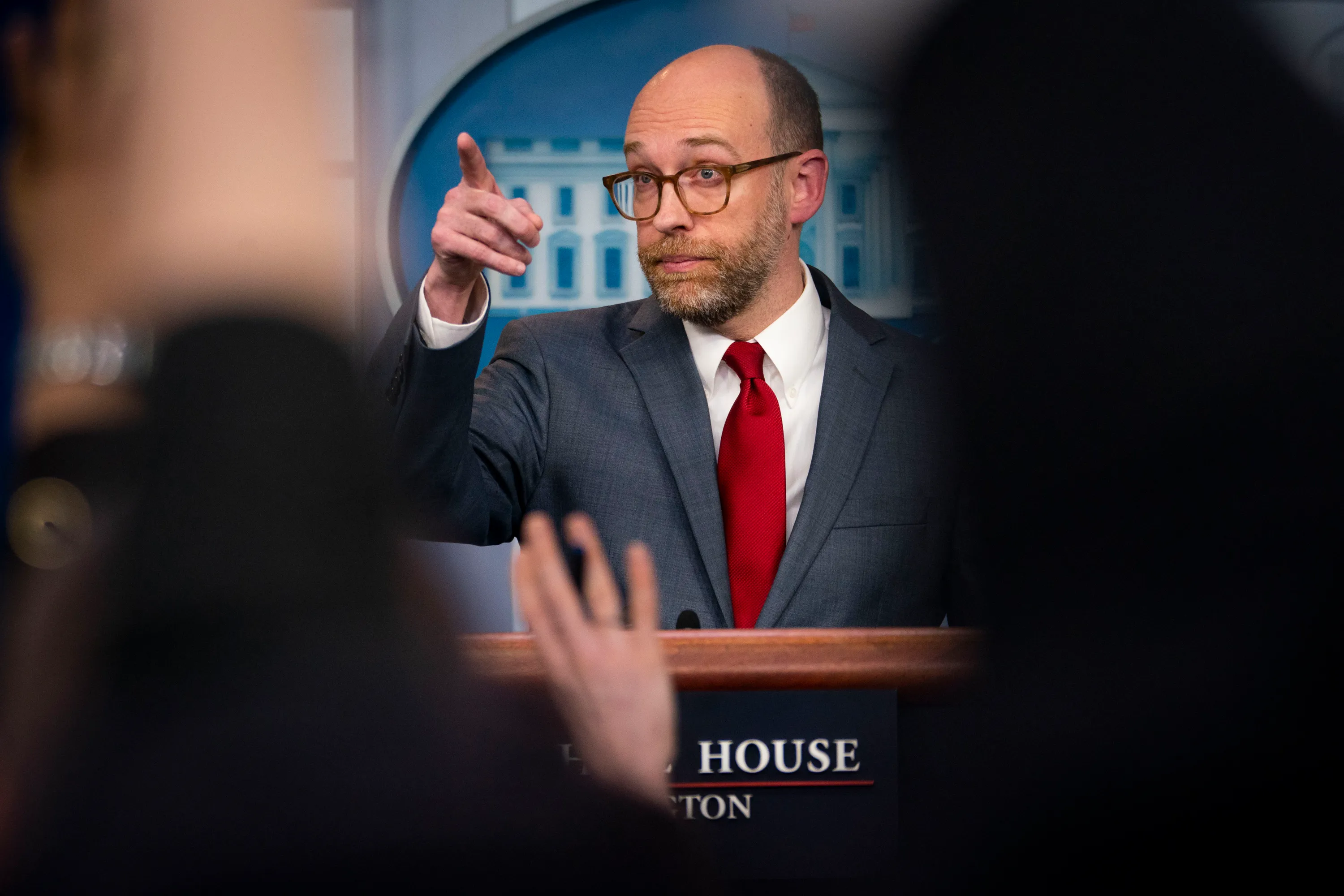 Vought points to a crowd while standing at a podium.