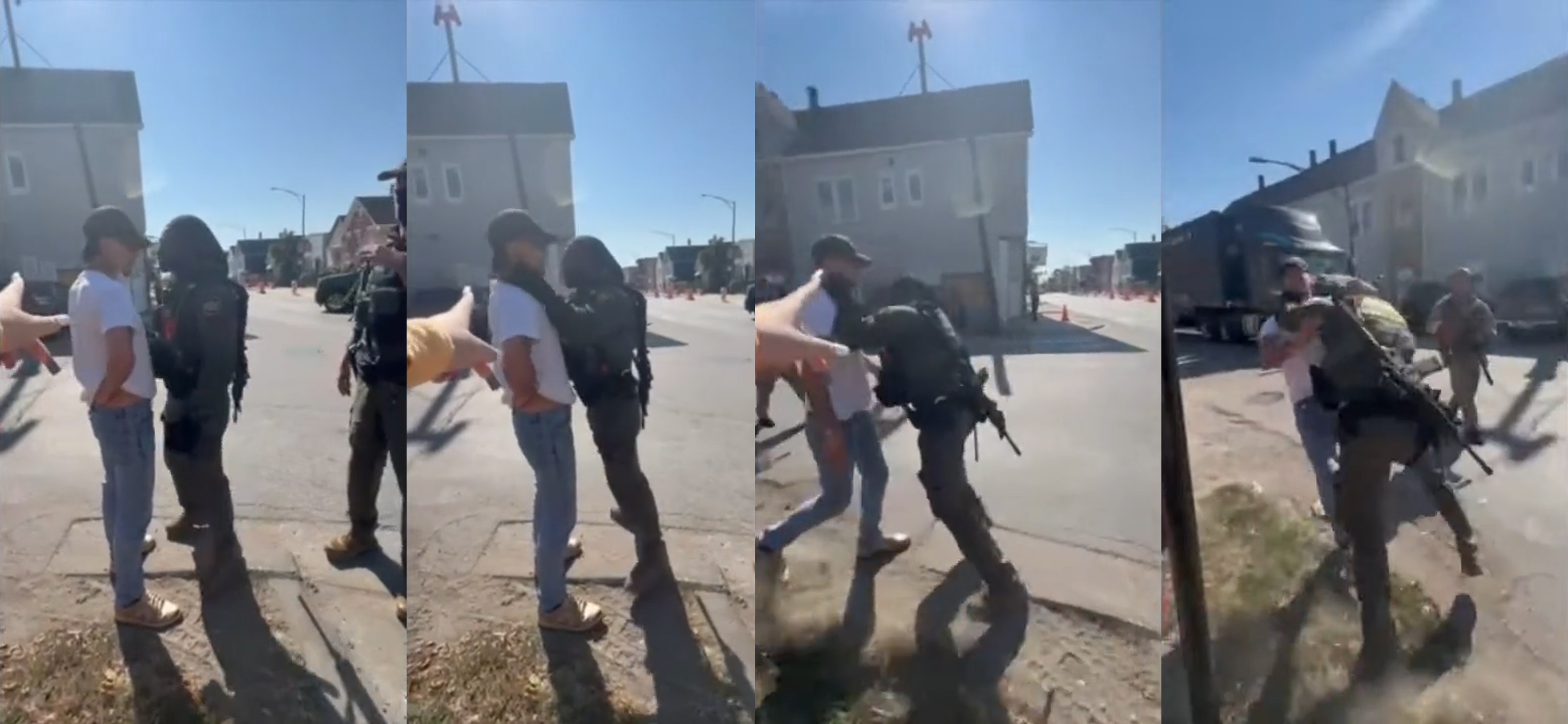 A uniformed Border Patrol officer with a large gun slung around his back has his hands around the neck of a man wearing jeans, a white T-shirt and a baseball hat in a residential neighborhood lined with houses.